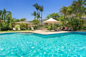uma piscina em frente a um edifício com palmeiras em Quamby Place, Apt 65 - Garden View em Noosa Heads