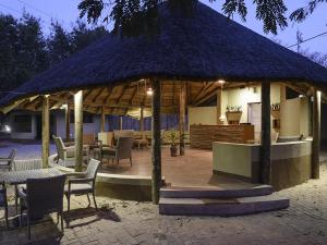 a pavilion with chairs and tables and a roof at Montebelo Gorongosa Lodge & Safari in Chitengo