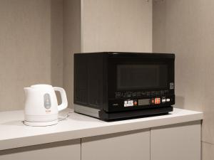 un horno microondas sentado en la parte superior de un mostrador en Hotel Plus Hostel SAPPORO, en Sapporo