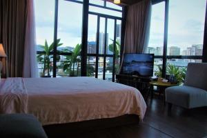 una camera con letto, TV e finestre di Oasis Hotel & Apartment a Da Nang