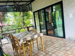 a table and chairs on a patio with a balcony at Ban Aob Maiy(บ้านโอบไม้) in Ban Si Wicha