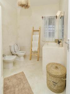 a white bathroom with a toilet and a sink at Cacuki Boutique House in Watamu