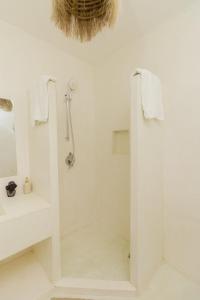 a white bathroom with a shower and a sink at Cacuki Boutique House in Watamu