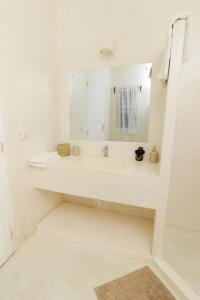 a white bathroom with a sink and a mirror at Cacuki Boutique House in Watamu