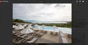 a view of a pool with chairs and umbrellas at Mantra Samui Resort - Adults Only in Mae Nam
