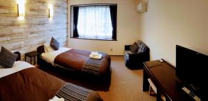 um quarto de hotel com duas camas e uma televisão em White Tree Lodge Madarao Tangram em Shinano