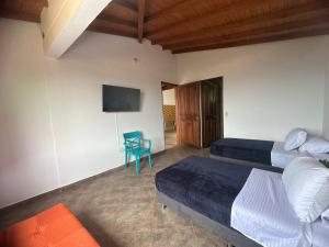 1 dormitorio con 2 camas, TV y silla en Aloja-T en Casa amoblada en Jericó, en Jericó