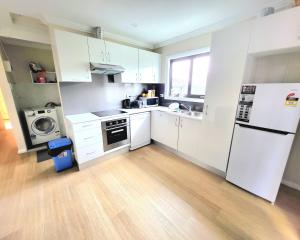 Una cocina con gabinetes blancos y un refrigerador blanco. en Kaban Power 7, en Doonside