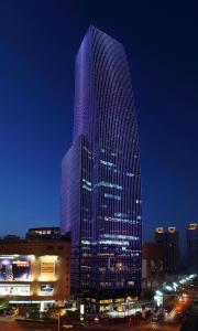 um edifício alto com luzes roxas à noite em Renaissance Shanghai Zhongshan Park Hotel em Xangai