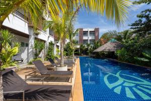 a swimming pool with chaise lounge chairs next to a building at 1Br Poolside Apartment, Long Beach, Lanta Sport Resort 109 in Ko Lanta