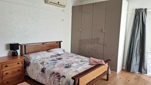 1 dormitorio con 1 cama, vestidor de madera y tocador en A cozy place en Noble Park