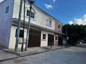 a white building with brown doors on a street at Chalchuapa, Santa Ana La Casa de Sussy, El Salvador in Chalchuapa
