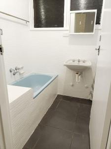 a white bathroom with a sink and a tub at PROMO! Entire 2 Bedroom Unit Near Train Station! Free Parking & Wifi! in Melbourne
