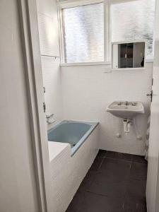 a bathroom with a tub and a sink and a window at PROMO! Entire 2 Bedroom Unit Near Train Station! Free Parking & Wifi! in Melbourne