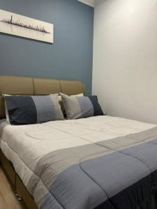a bed in a bedroom with a blue wall at Spacious Home @ Kuching City Ctr in Kuching