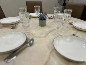 a table with white plates and glasses on it at Spacious Home @ Kuching City Ctr in Kuching
