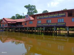 un edificio rosso accanto a un corpo idrico di Yussal Homestay a Simpang Ampat Semanggol
