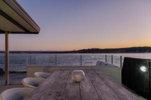 - une table en bois avec des chaises et une vue sur l'eau dans l'établissement 690 Pukehina - Whare Nui, à Pukehina