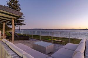 a patio with a couch and a view of the water at 690 Pukehina - Whare Nui in Pukehina