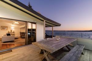 a wooden table on the deck of a house at Pukehina Estuary Sunset Views Holiday Home in Pukehina