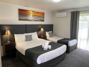 a hotel room with two beds and two lamps at Frankston Motel in Frankston