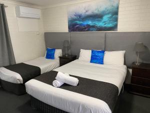 Habitación de hotel con 2 camas y almohadas azules en Frankston Motel, en Frankston