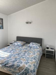 a bed with a blue and white comforter in a bedroom at Appartement vue mer in La Guérinière