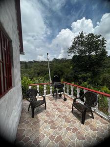 Un patio con sillas y una mesa en el balcón. en Cabaña Chalet La Lomita, en San Gil