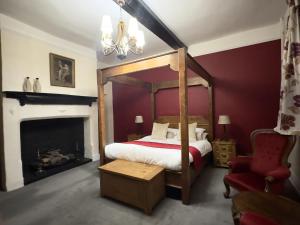 a bedroom with a canopy bed and a fireplace at Scole Inn Hotel in Diss
