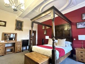 a bedroom with a canopy bed and a desk at Scole Inn Hotel in Diss
