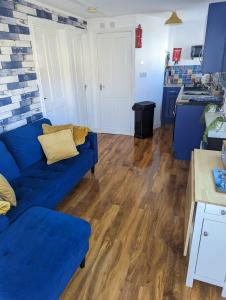 uma sala de estar com um sofá azul e uma cozinha em Savannah-by-the-sea em Bridlington