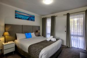 um quarto com uma cama grande e 2 janelas em Frankston Motel em Frankston