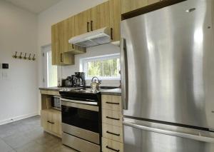 a kitchen with a stainless steel refrigerator at Chalet L'Écureuil (waterfront, modern, spa, BBQ) in Chertsey