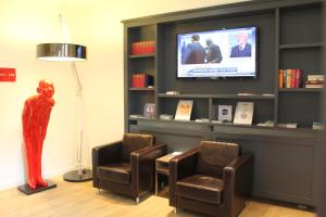 a waiting room with two chairs and a television at Gideon Hotel in Nuremberg