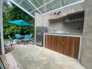 an outdoor kitchen with a table and an umbrella at Serenity Glamping in Puerto Viejo