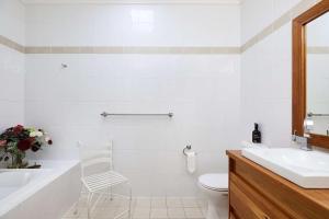 bagno con vasca bianca, lavandino e sedia di Arabella a Nelson Bay