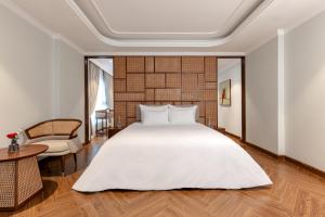 a bedroom with a large white bed and a table at La Siesta Classic Hang Thung in Hanoi