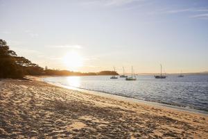 a beach with boats in the water at sunset at No 6 ShoalHaven in Shoal Bay +5 photos