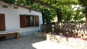 a patio with a stone wall and a bench and flowers at Homestead Vrbin in Divača