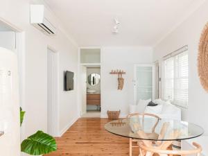 a white living room with a glass table and chairs at No 3 ShoalHaven - 1 bed option in Shoal Bay