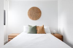 a bedroom with a bed with white sheets and pillows at Surf Mist in Newcastle