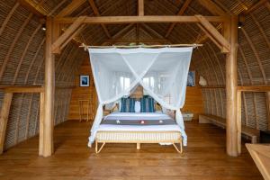 um quarto com uma cama de dossel numa cabana de palha em Morin Resort em Nusa Lembongan
