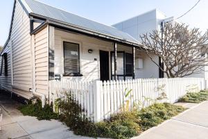 a house with a white fence in front of it at Pattys Cottage - Pet friendly home in Merewether in Merewether