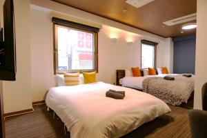 une chambre avec deux lits et deux fenêtres dans l'établissement J-Court Oshiage, à Tokyo