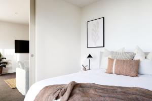 Un dormitorio con una cama blanca con una manta. en The Cove, en Newcastle