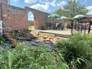 a brick wall with an outdoor patio with a creek at Scole Inn Hotel in Diss