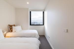 two beds in a white room with a window at The Edge in Newcastle