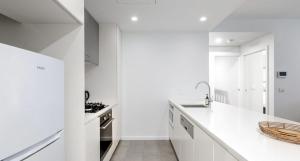 a white kitchen with white cabinets and a sink at The Muse - 1 bed option in Newcastle