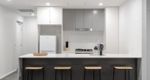 a kitchen with white cabinets and a counter with stools at The Muse in Newcastle