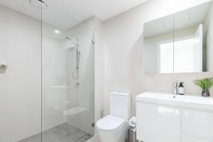 La salle de bains blanche est pourvue d'une douche et de toilettes. dans l'établissement The Hideaway, à Newcastle